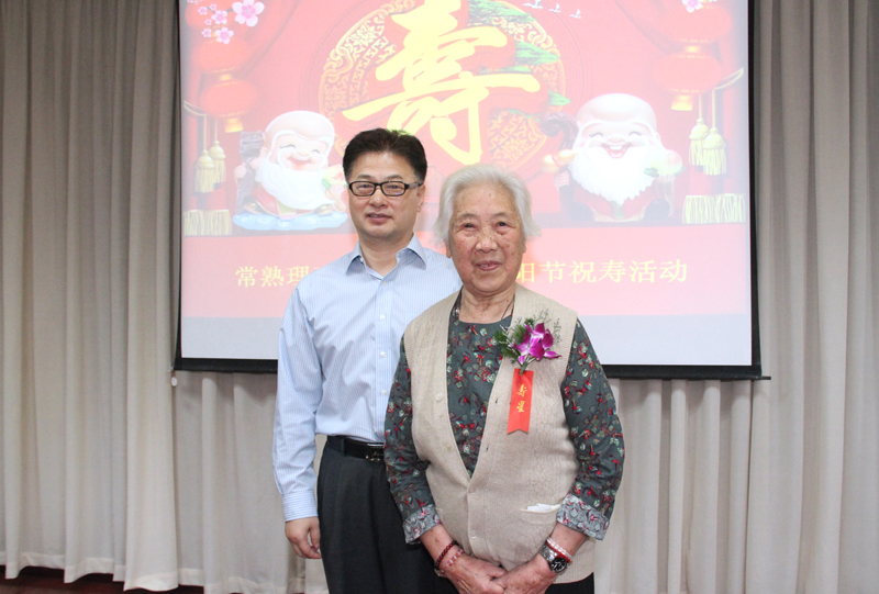 副校长周宏给90岁寿星佩戴胸花并合影.jpg